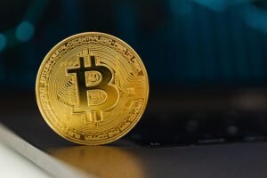Golden Bitcoin standing upright on a laptop keyboard, representing digital currency.